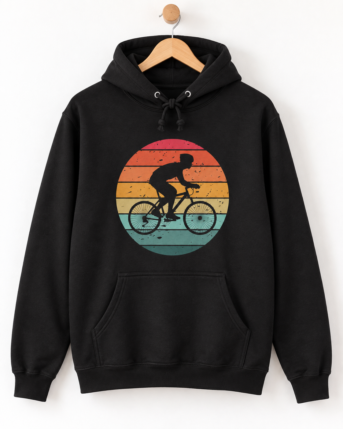 A black pullover hoodie hanging on a wooden hanger against a plain white wall. The hoodie features a large circular retro sunset graphic on the chest with a black silhouette of a cyclist riding a bicycle.