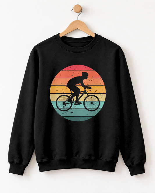 Deep black crewneck adult sweatshirt featuring a cyclist silhouette against a distressed striped sunset graphic styled on a wooden hanger.