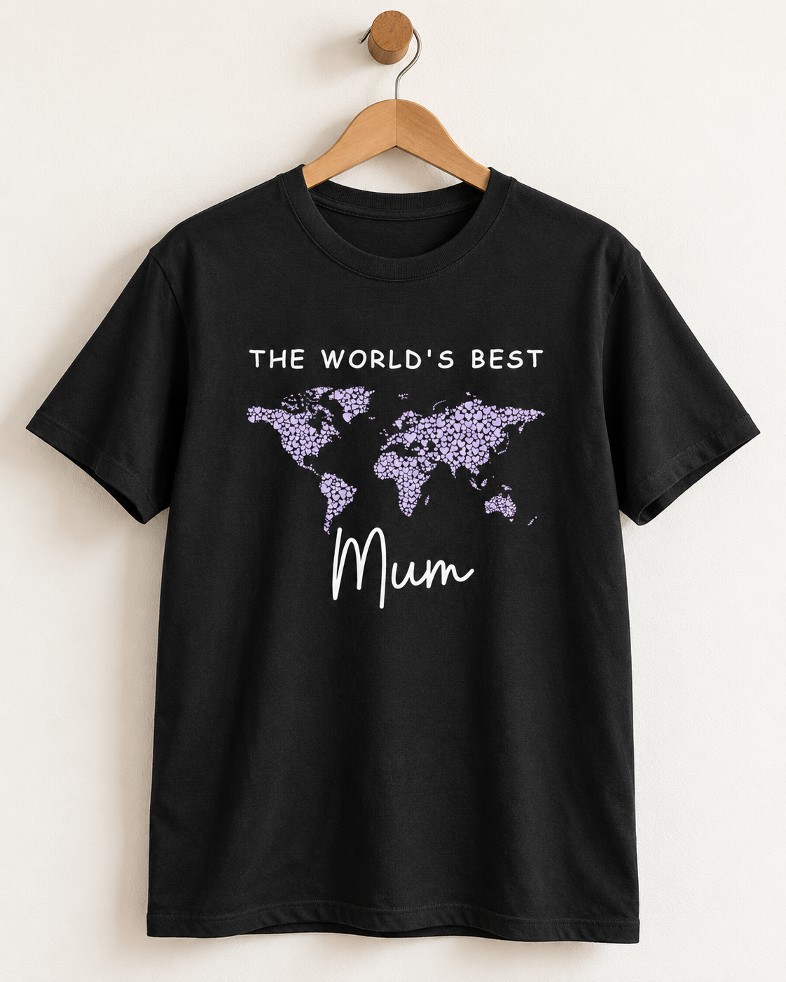 Black T-shirt on a wooden hanger with a lilac world map made of hearts and white “The World’s Best Mum” lettering.
