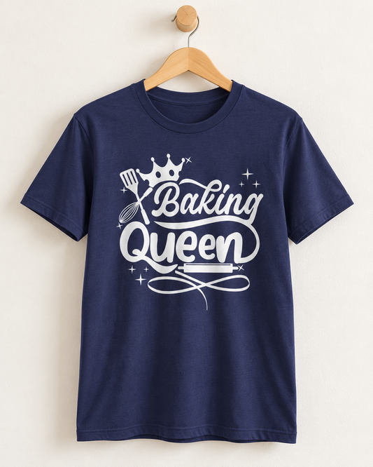 A navy blue short-sleeve t-shirt hanging on a wooden hanger against a light beige wall. The shirt features a white graphic print on the front with the words 'Baking Queen' in a stylized script, decorated with a crown, spatula, whisk, and star accents.