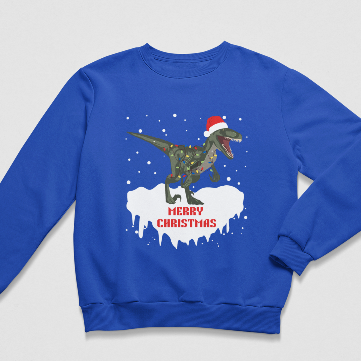Royal blue kids Christmas sweatshirt featuring a roaring T-Rex wearing a Santa hat, wrapped in colourful Christmas lights with falling snow and Merry Christmas text.