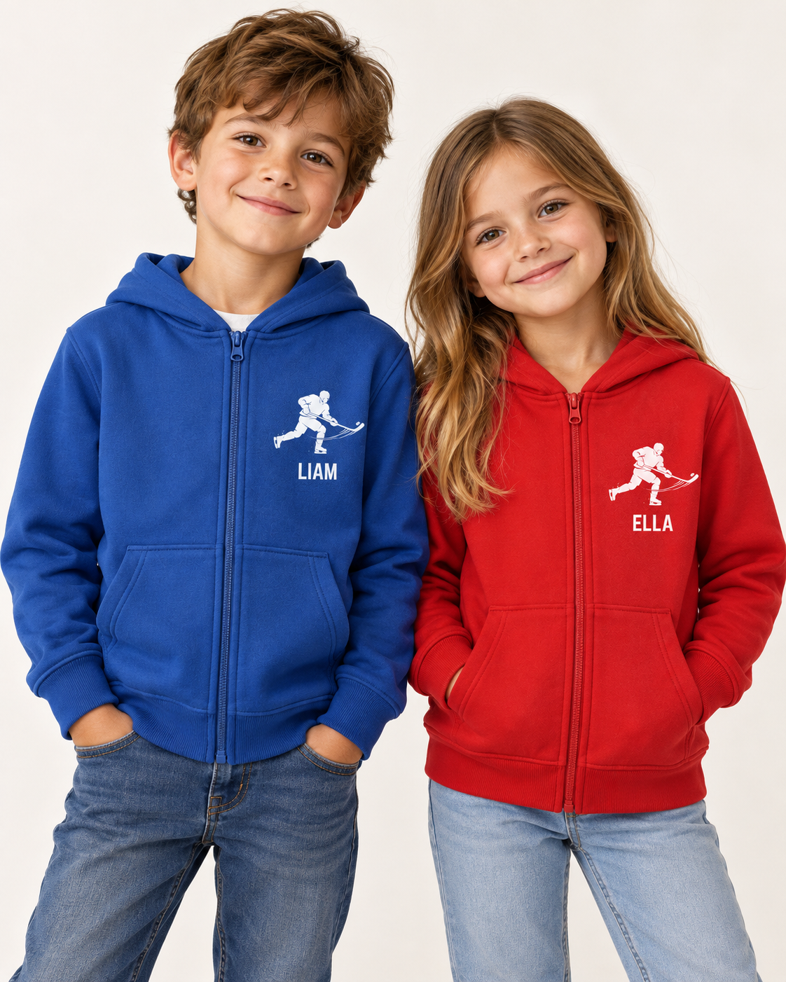 A boy and a girl wearing personalized zip-up hoodies, with the boy on the left in a royal blue hoodie and the girl on the right in a red hoodie. Both hoodies feature a white hockey player graphic and the name printed below it (LIAM and ELLA respectively).