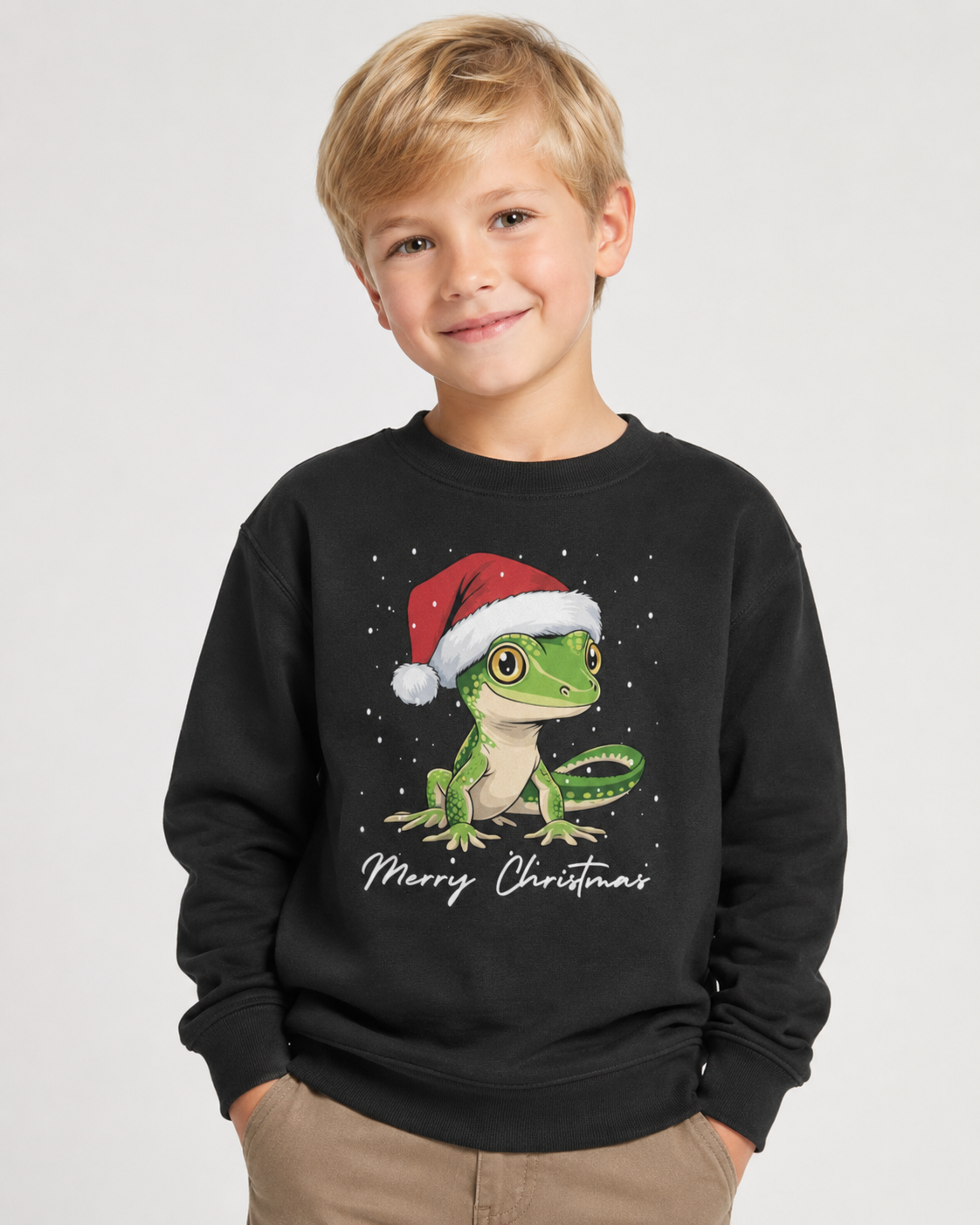 7-year-old blonde boy wearing a black Christmas jumper featuring a green gecko in a Santa hat with Merry Christmas text.