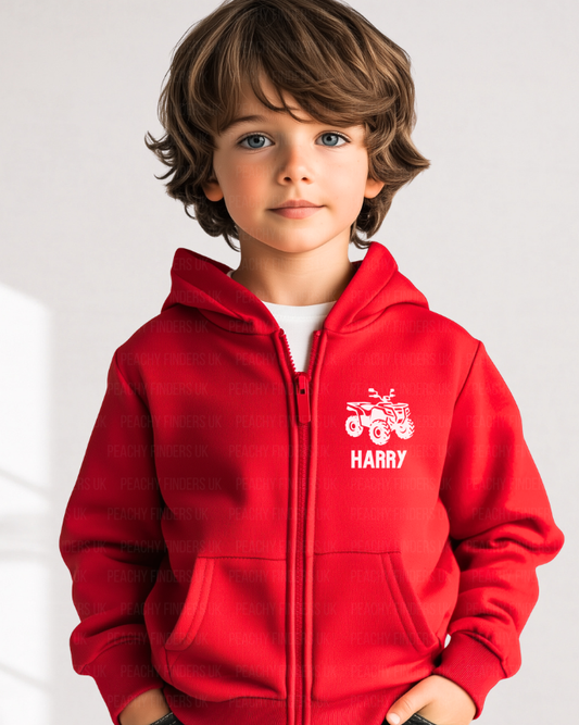 Boy modelling a red zip hoodie with a white quad bike logo and name in a studio setting. 