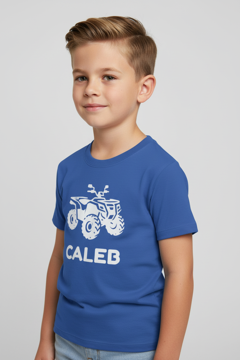 Close-up of boy wearing a royal blue custom name quad bike kids t-shirt with white ATV silhouette and the name “Caleb”, studio background.