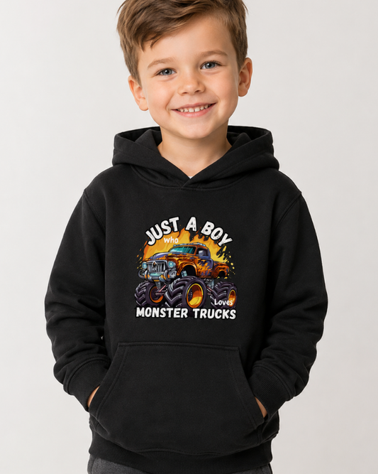 Young child wearing a black “Just a Boy Who Loves Monster Trucks” hoodie with colourful monster truck graphic on the front.