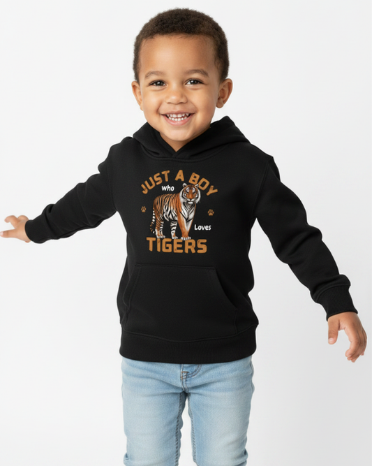 A happy young boy wearing a black pullover hoodie featuring a bold tiger graphic and the slogan "Just a Boy Who Loves Tigers" – studio photography
