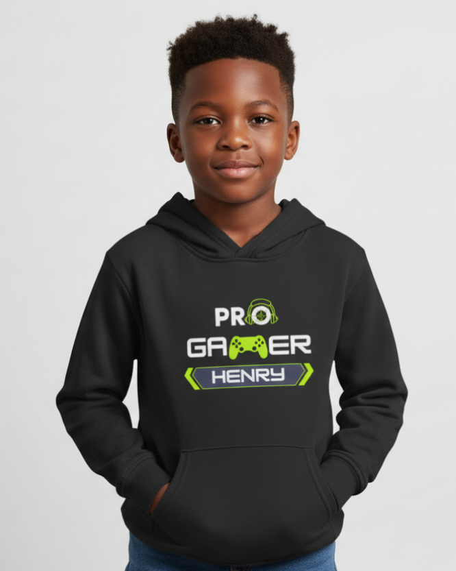 Young boy modelling black kids personalised “PRO Gamer” hoodie with lime green gaming graphic and custom name on chest, hands in pocket, studio background.
