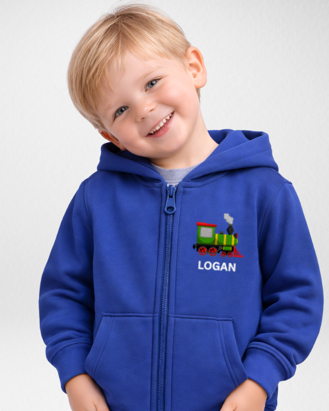 Smiling toddler wearing a royal blue personalised steam train zip hoodie with name on the chest, studio white background.