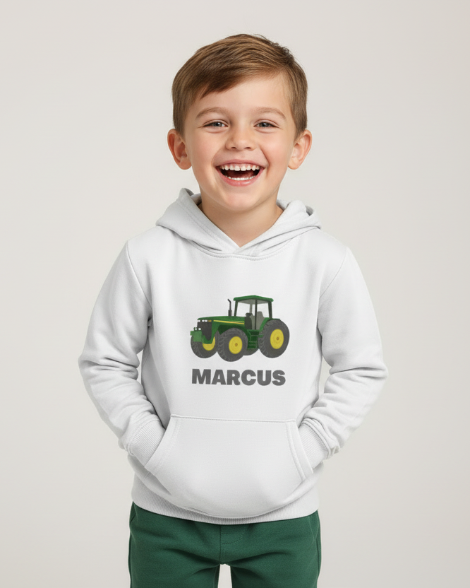 Smiling boy modelling white custom name tractor hoodie in studio, hands in pocket, front design visible.