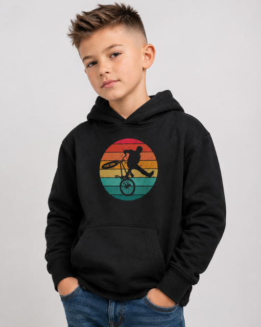 Boy wearing black retro BMX graphic kids hoodie with vintage BMX stunt design in studio setting