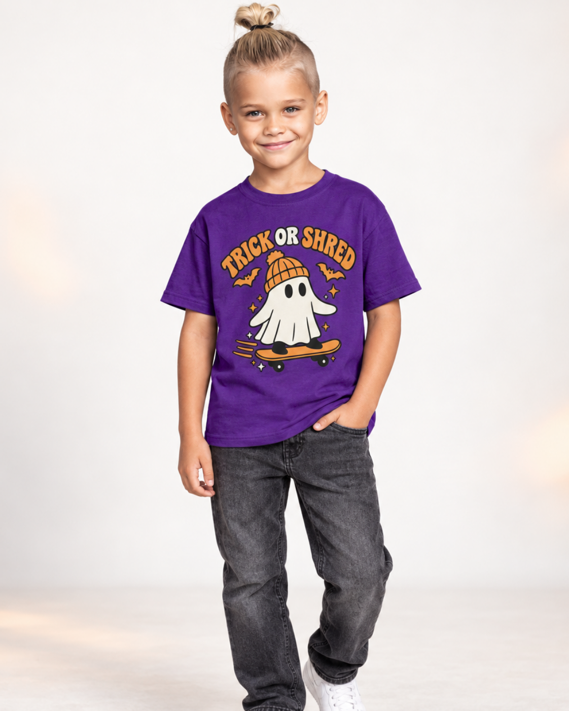 Boy wearing a purple Trick or Shred skateboarding ghost Halloween T-shirt
