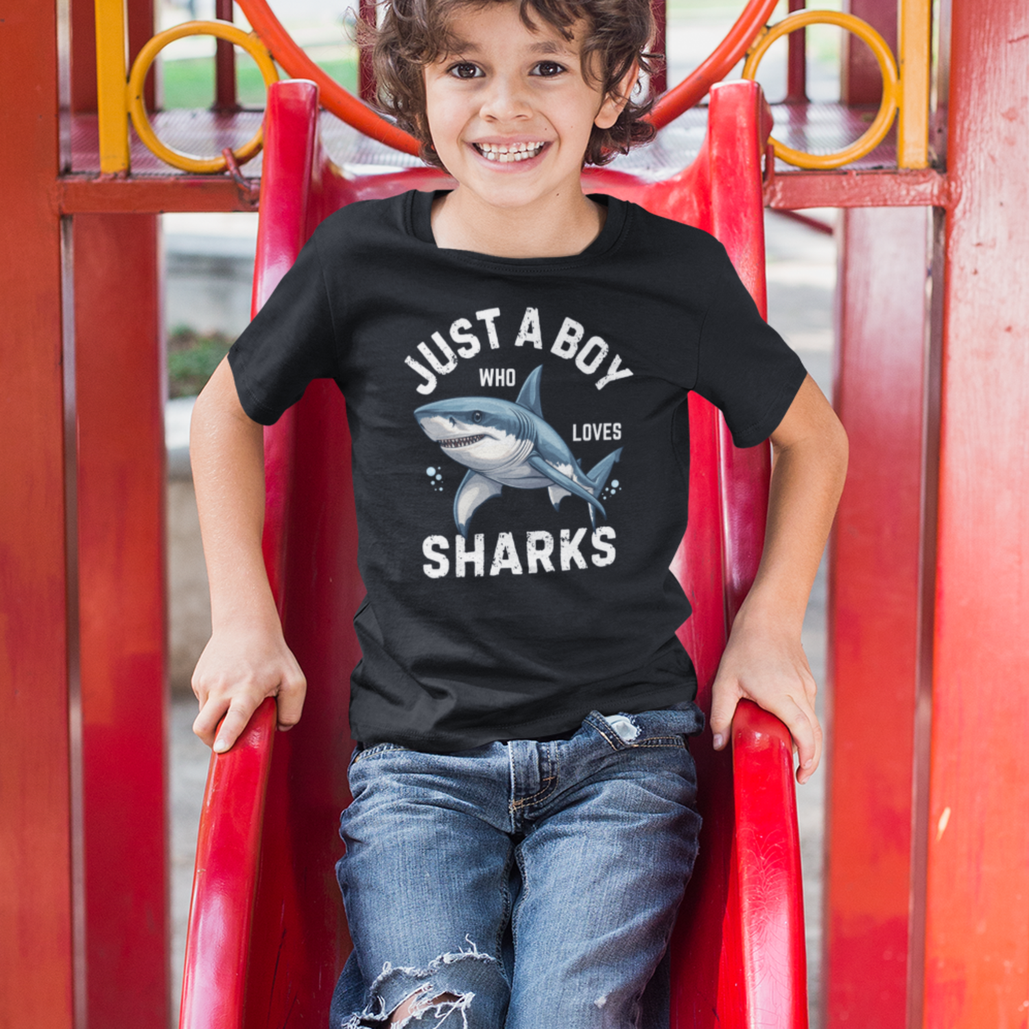A boy at the park wearing a black T-shirt with great white shark graphic and 'Just a Boy Who Loves Sharks' slogan