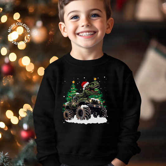 A child wearing a black sweatshirt with a graphic of a Christmas themed T-rex riding a monster truck 