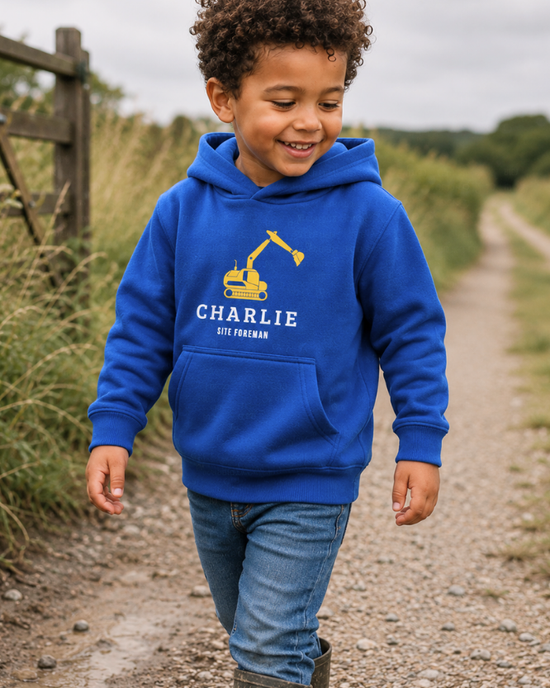 Little boy wearing personalised royal blue digger hoodie walking along countryside gravel path in muddy wellington boots.
