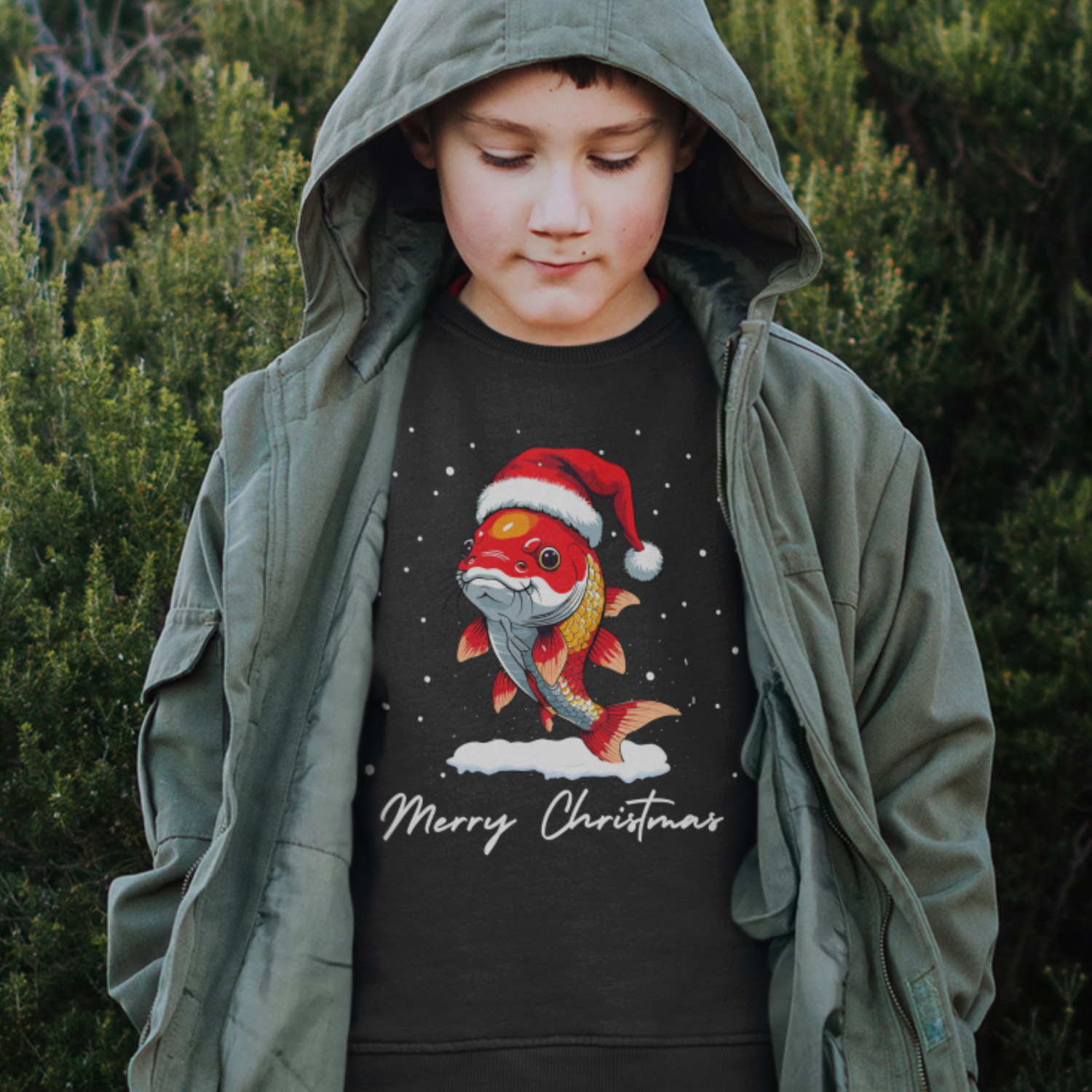 Young boy wearing a black jumper with a Christmas design of a koi carp fish wearing Santa hats, surrounded by falling snow.
