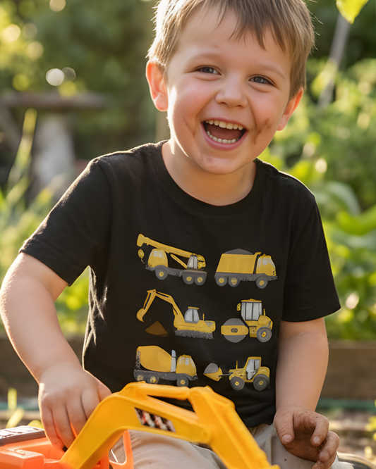Little boy wearing black construction vehicle T-shirt playing outdoors with toy digger.