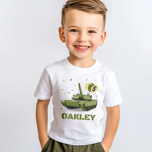 Smiling young boy wearing a personalised white birthday T-shirt with a green army tank, balloons and stars, and the name “Oakley” printed on the front.