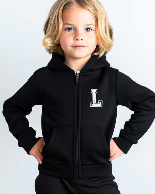 Young boy wearing a monogram black zip hoodie with a varsity college style white big letter 'L'