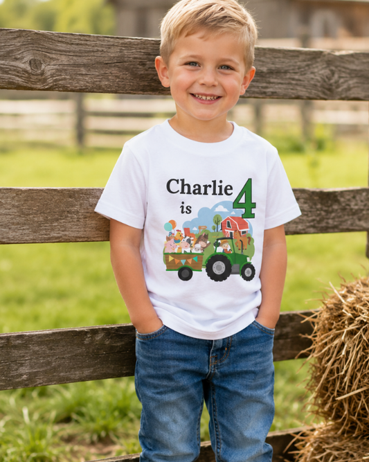 Boy wearing personalised farm tractor birthday T-shirt with name and age, standing by a rustic farm fence.