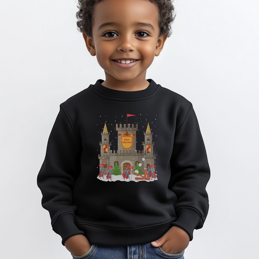A young boy wearing a black Christmas sweatshirt with a festive castle and knights design on a white background