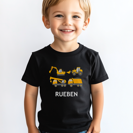A young boy wearing a black T-shirt with personalised construction vehicles and the name 'Rueben' printed on the front.