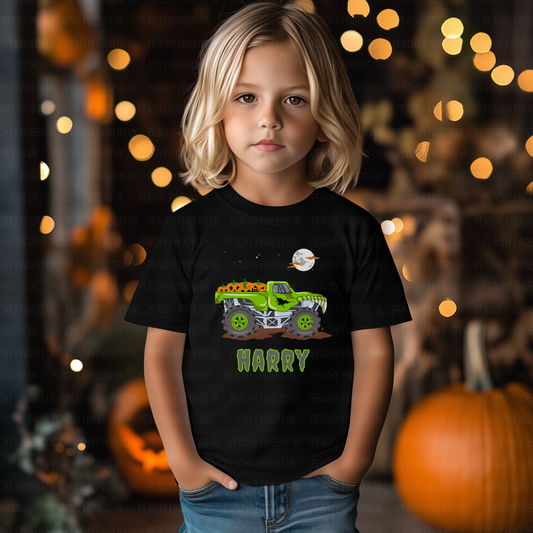 Child wearing a black t-shirt with a green monster truck graphic and name 'Harry', standing in front of Halloween decorations.