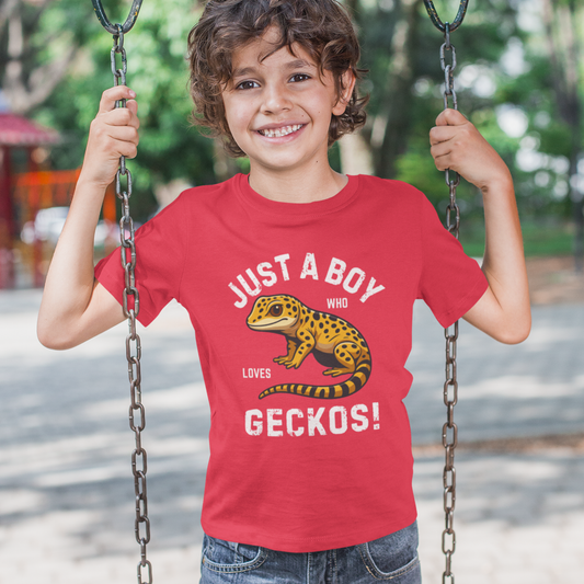 Child wearing a red t-shirt with a gecko graphic and "just a boy who loves geckos" text