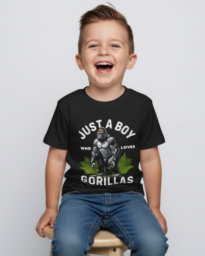 Smiling boy sitting on stool wearing black gorilla graphic kids t-shirt, "Just a Boy Who Loves Gorillas" design, clear front print detail, studio background
