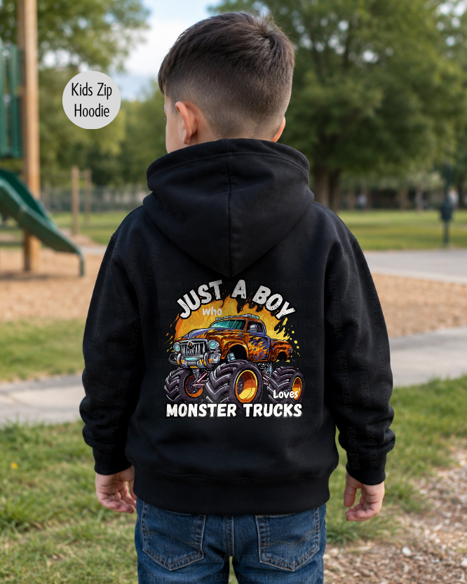 Boy wearing a black “Just a Boy Who Loves Monster Trucks” back print hoodie, shown from behind in an outdoor park setting.