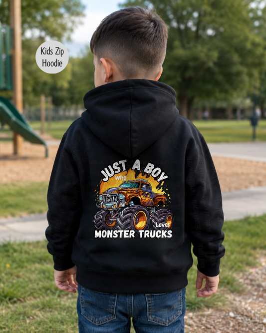 Boy wearing a black “Just a Boy Who Loves Monster Trucks” back print hoodie, shown from behind in an outdoor park setting.