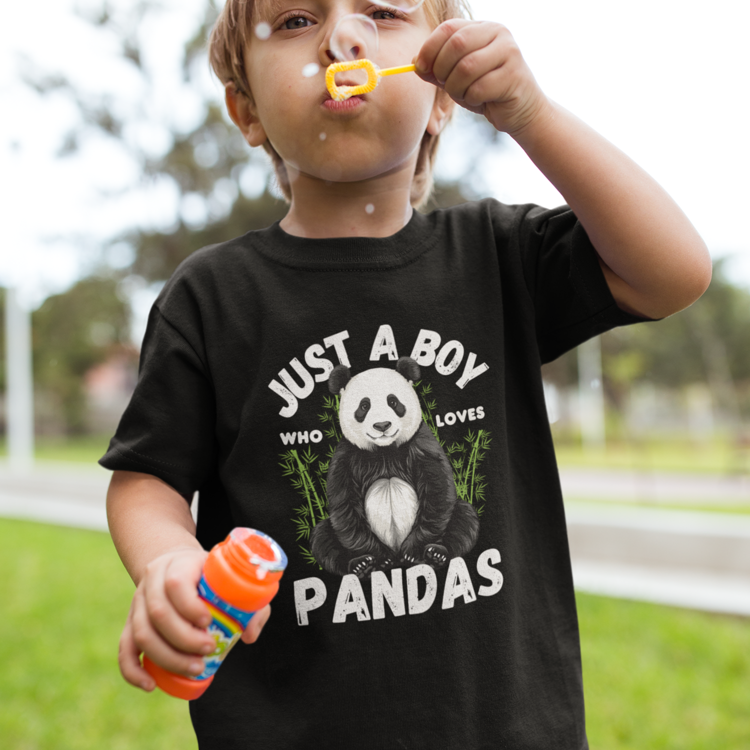Child blowing bubbles wearing a black t-shirt with a panda design and text.