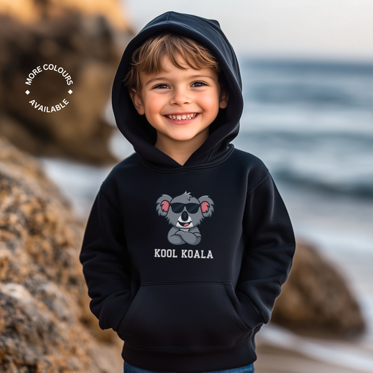 Smiling young boy wearing a black Kool Koala hoodie with a cartoon koala in sunglasses and the words ‘Kool Koala’ printed on the front.