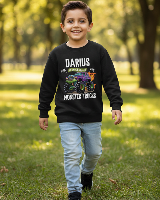 Happy boy walking in park wearing black personalised “Darius is mad about Monster Trucks” kids sweatshirt with bold truck graphic.