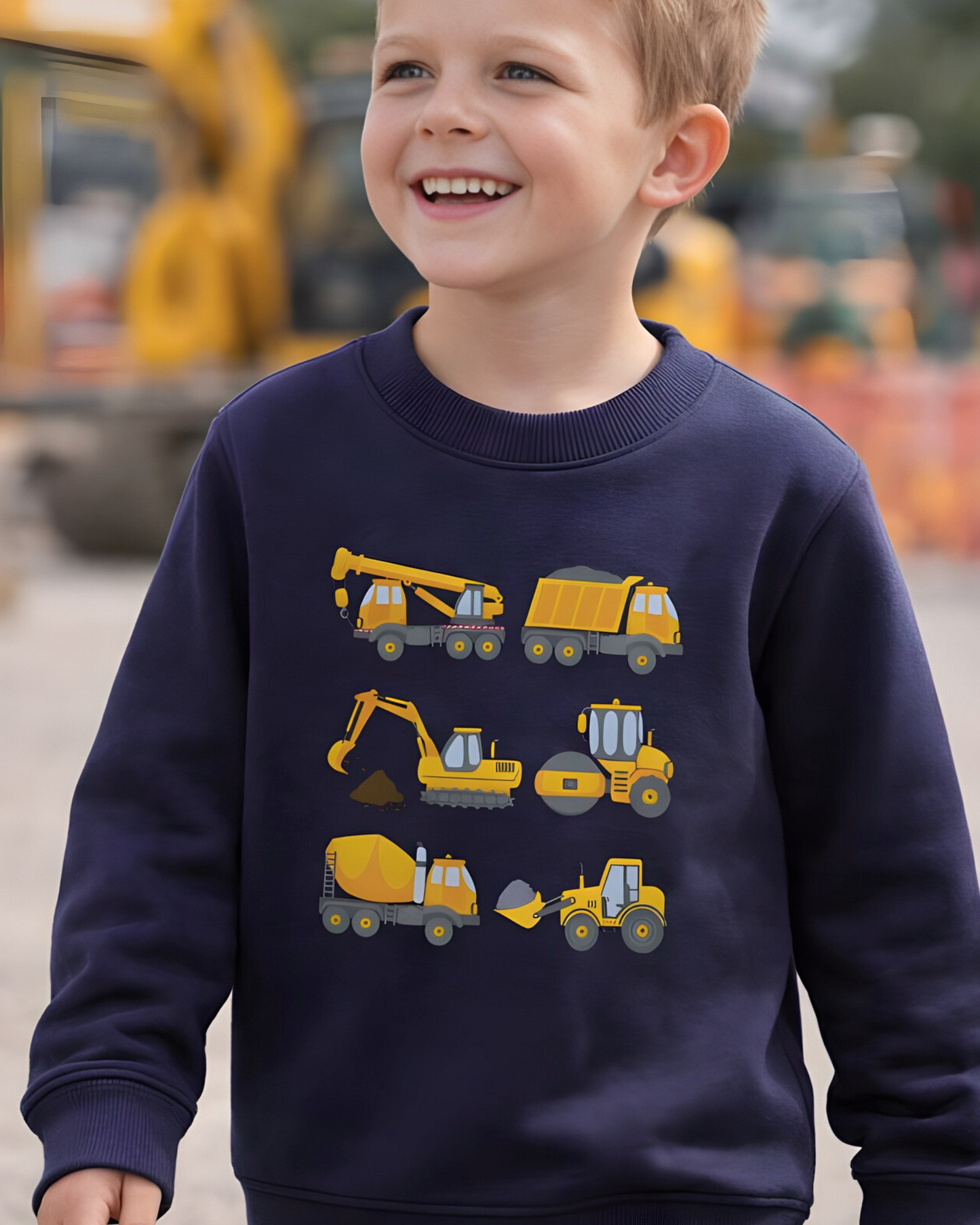 A young boy wearing wearing a navy blue sweatshirt with construction vehicle graphics in an outdoor setting.