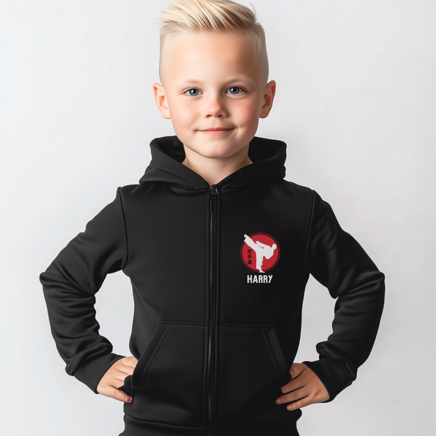 Young boy wearing a black personalised karate zip hoodie with a red martial arts emblem and the name "Harry" printed on the left chest. 