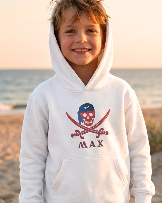 Boy wearing white personalised pirate skull and crossbones hoodie with name Max at the beach