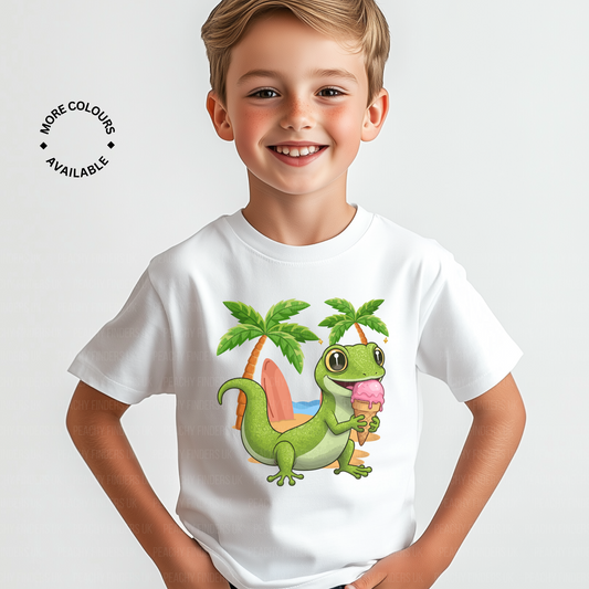 Smiling boy wearing a kids gecko T-shirt with a green gecko holding ice-cream on a beach with palm trees in the background.