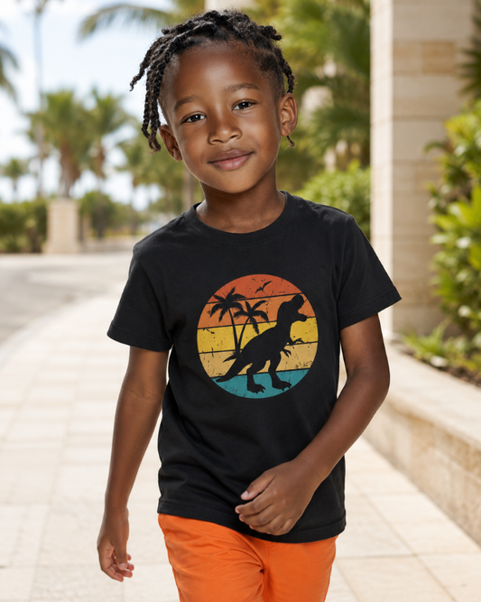 Boy wearing dinosaur t-shirt with colourful sunset palm tree graphic in black, paired with orange summer shorts