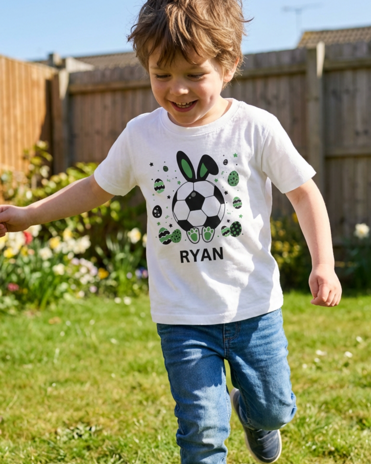 Young boy wearing a white personalised football Easter bunny T-shirt with custom name, featuring a bunny football and green Easter egg design