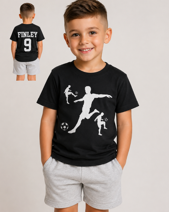 A young boy wearing a black short-sleeve t-shirt with white soccer player silhouettes graphic on the front and 'FINLEY 9' printed on the back, paired with light grey shorts. A smaller inset image in the top left shows the back view of the shirt.