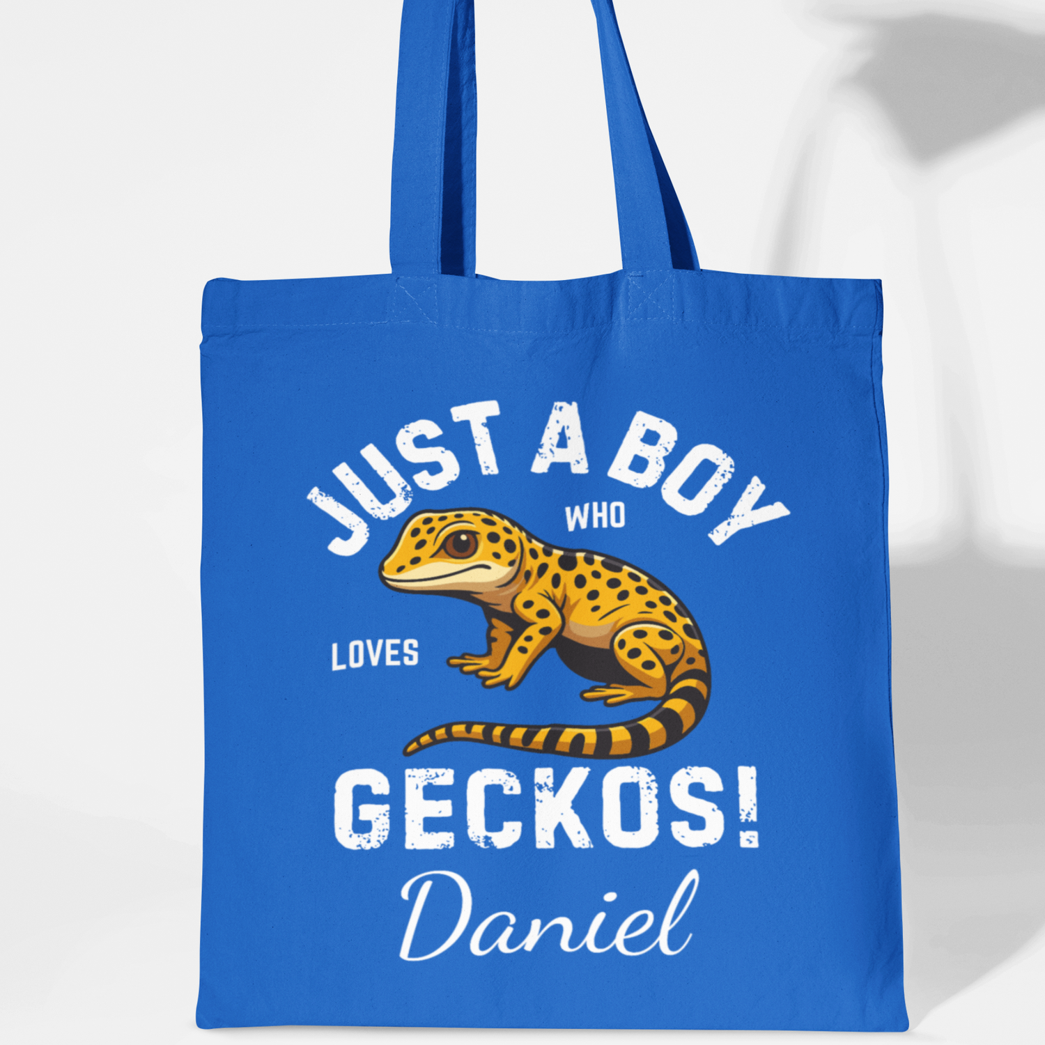 Royal blue kids tote bag with “Just A Boy Who Loves Geckos!” slogan, yellow gecko illustration and personalised name “Daniel” underneath.