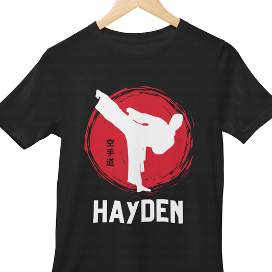 Kids black t-shirt with a white silhouette of a person doing a martial arts move, red circle, personalised name 'Hayden' on a hanger.