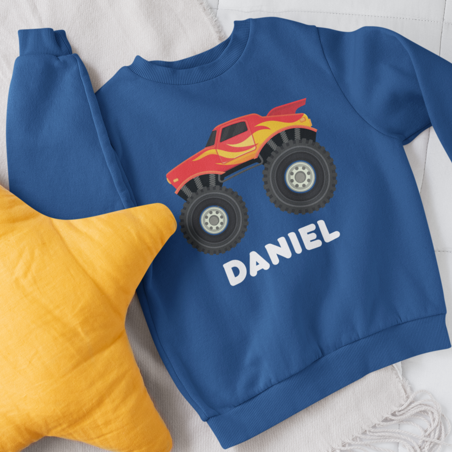 A blue sweatshirt with a printed monster truck and personalised name in white 