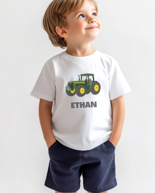 A young boy wearing a white t-shirt with a green and yellow tractor graphic and the name 'ETHAN' printed on the front.
