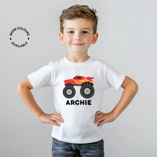 A child wearing a white personalized t-shirt with a red and black monster truck design and the name 'ARCHIE' printed on the front.