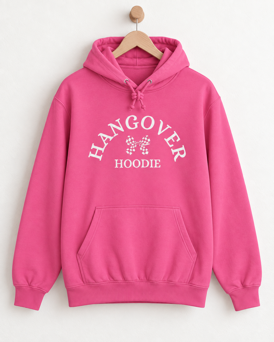 Ladies candy-floss pink adult Hangover Hoodie with white curved lettering and chequered bow design displayed on a wooden hanger.