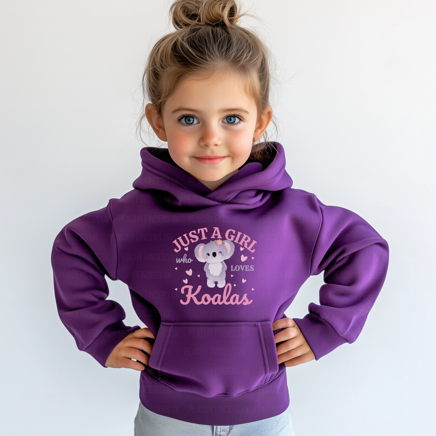 A young girl with blue eyes smiles, wearing a purple hoodie with a koala design and the text "JUST A GIRL who LOVES Koalas". Her hair is styled in a bun.