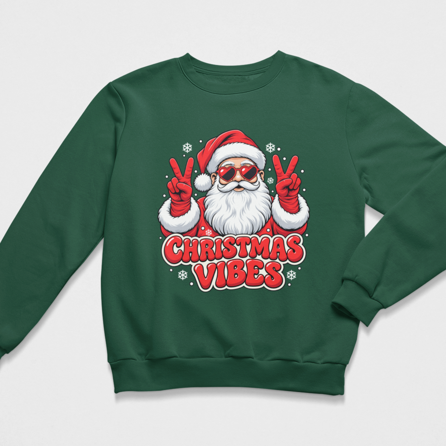 Flat lay of a kids dark green Christmas crewneck sweatshirt featuring an illustration of Santa Claus in heart-shaped sunglasses and red mittens making peace signs, set against falling snowflakes with the text "CHRISTMAS VIBES"