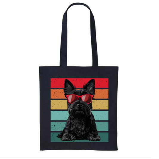 A black canvas tote bag featuring a graphic of a black Scottish Terrier wearing red sunglasses against a retro striped background in shades of red, orange, yellow, and teal.